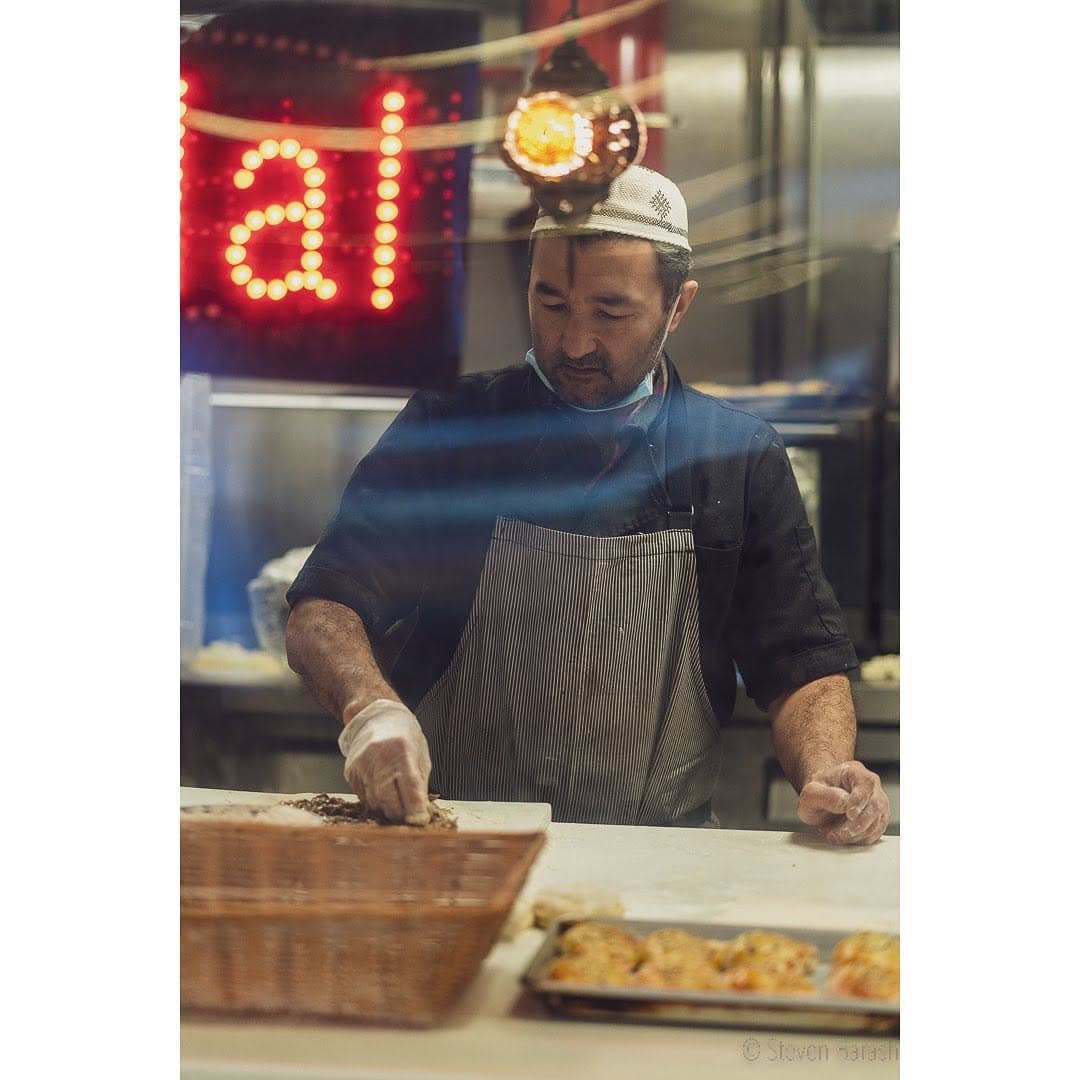 A food-service worker prepares food behind a restaurant window.